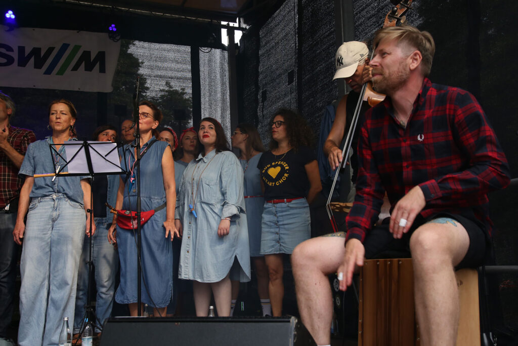 Bud Spenzer Heart Chor beim Isarinselfest 2024. Sängerinnen, Bassist und Cajonist